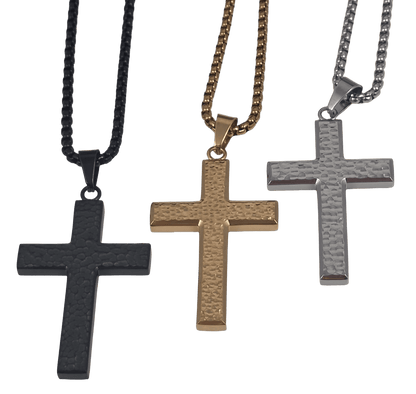 straight view of an all-black or all gold and all silver IP-plated stainless steel cross pendant featuring a rugged, hammered dimple texture on the main body, framed by polished edges, hanging on a black box chain against a black background.
